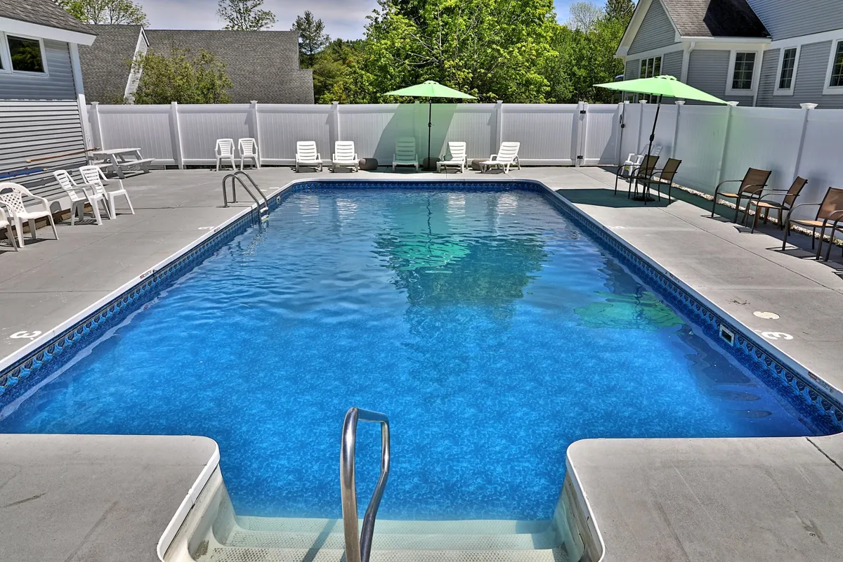 This image captures the property's outdoor swimming pool area, complete with inviting lounge chairs and umbrellas set up for relaxation. The pool is surrounded by greenery, creating an appealing space for guests to unwind and enjoy the fresh Vermont air. The scene conveys a leisurely, nature-connected atmosphere ideal for eco-friendly escapes.