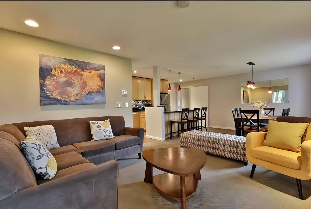 An open-plan area that includes a comfortable sofa, a vibrant yellow chair, tasteful artwork, and a spacious dining table. The layout encourages conversation, group meals, and community, combining relaxation and dining in one harmonious space.