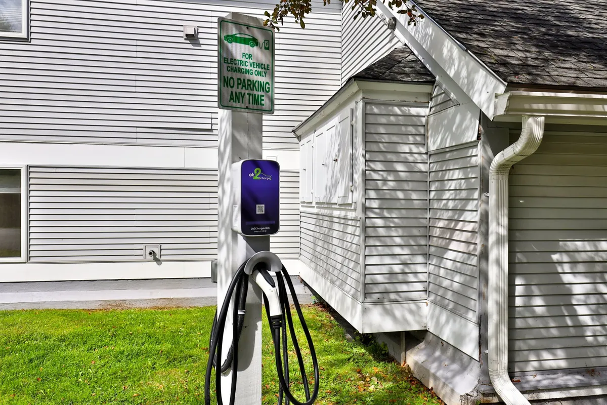 A modern electric vehicle charging station positioned near the building, with clear signage and contemporary architectural elements in the background. The area is well-maintained, highlighting the property's commitment to sustainability and convenience for eco-conscious travelers.